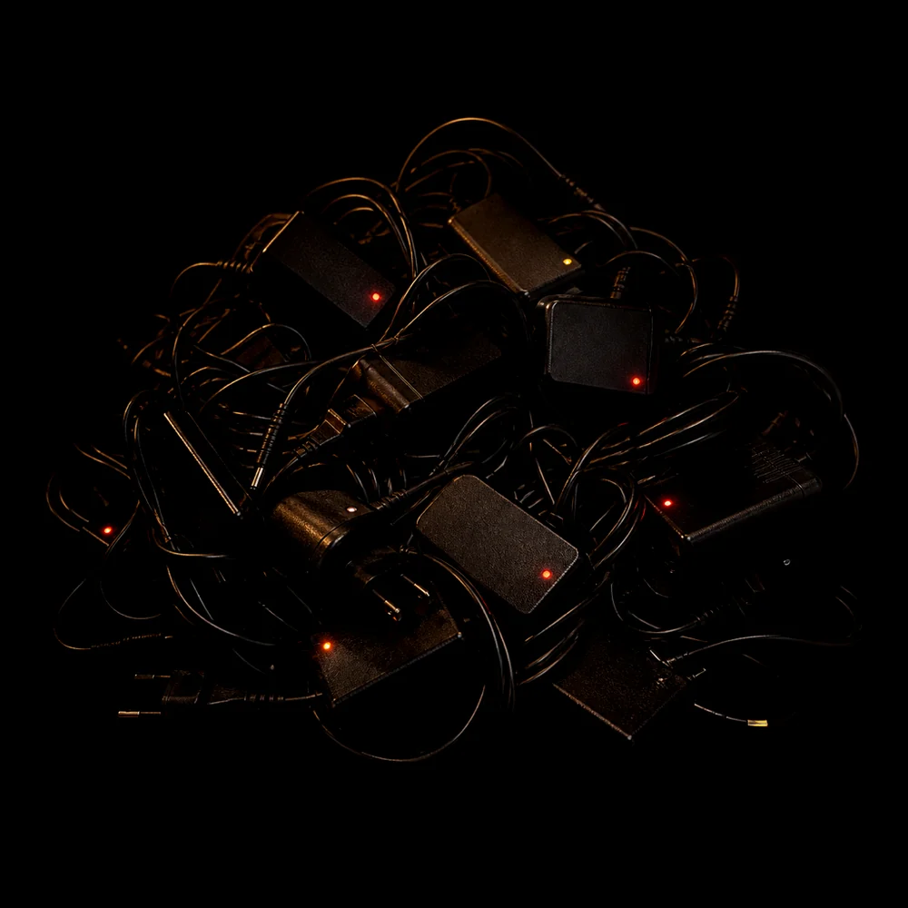 A tangle of plug adapters in darkness, standby LEDs glowing